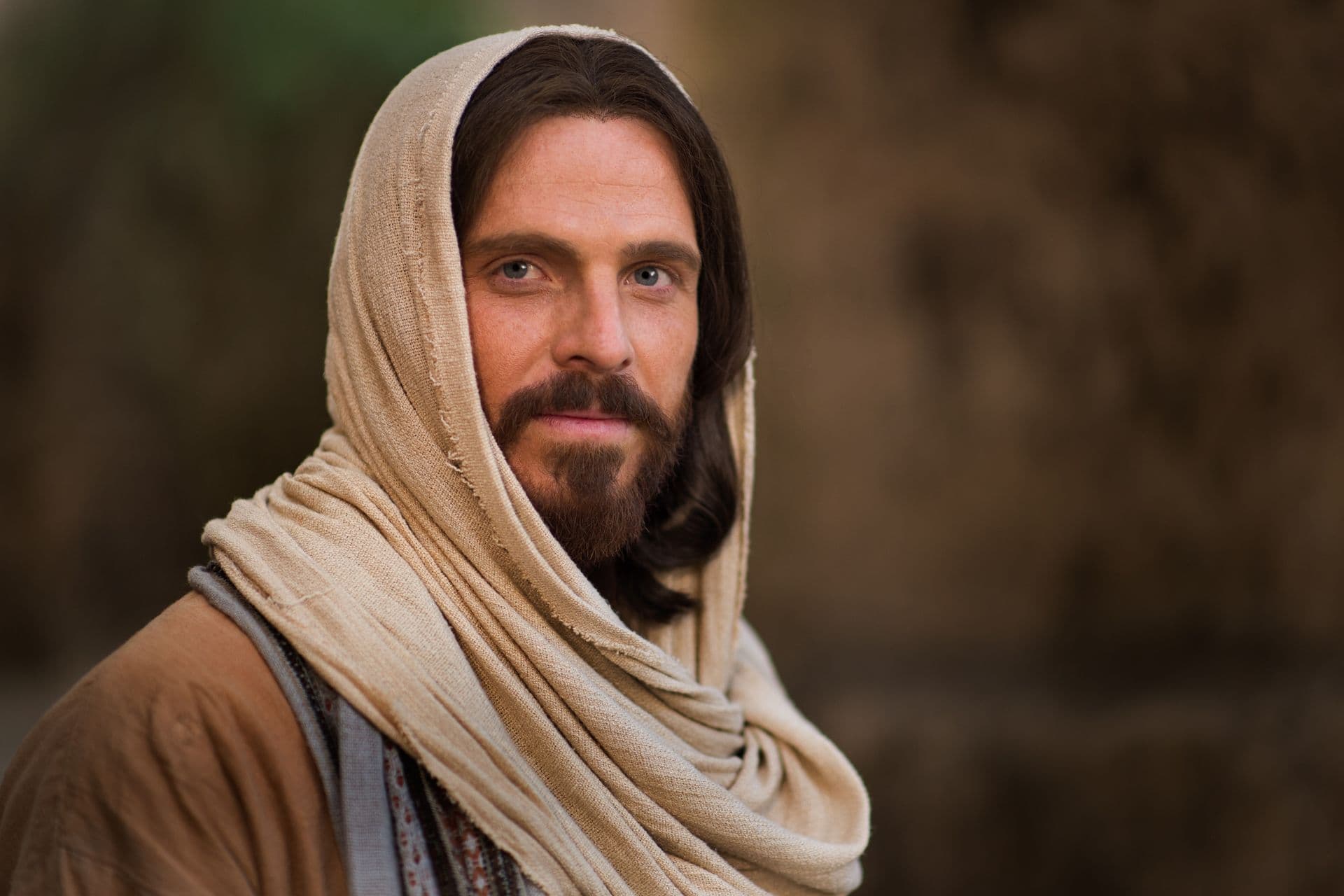 A portrait of Jesus Christ in a cream head covering and robe, looking toward the viewer.